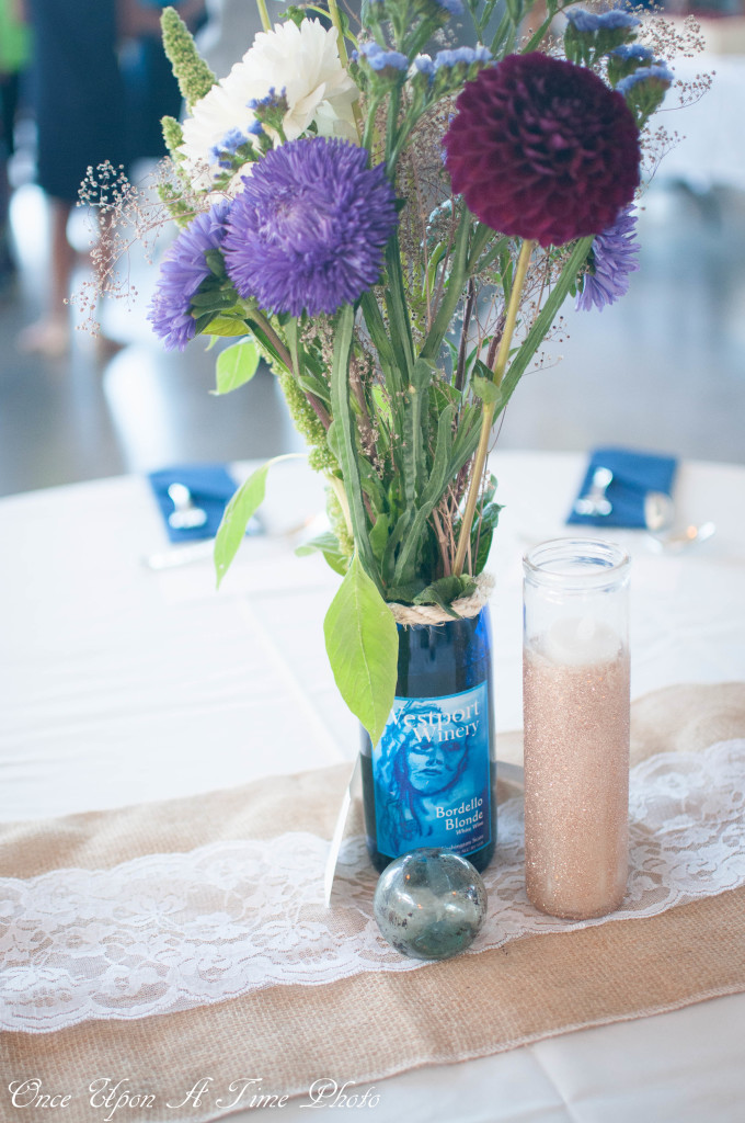 Nautical wedding centerpieces with Farmer's Market flowers, blue and green wine bottle vases, sea glass, and candles. Every other table had a burlap and lace table runner or a navy blue and white table runner for this maritime wedding. | www.bexbernard.com
